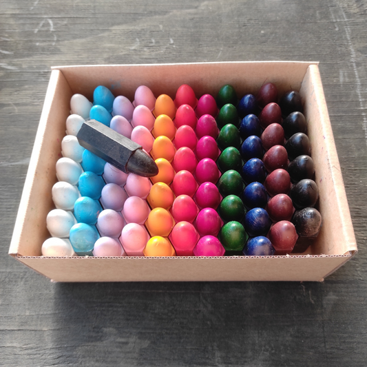 open box showing the tips of hexagonal crayons in eleven colours white, light blue, lilac, pink, yellow, orange, red, green, blue, brown and black